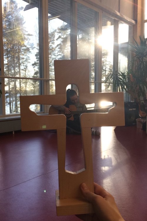 Kuva rististä ja tytöstä joka soittaa kitaraa